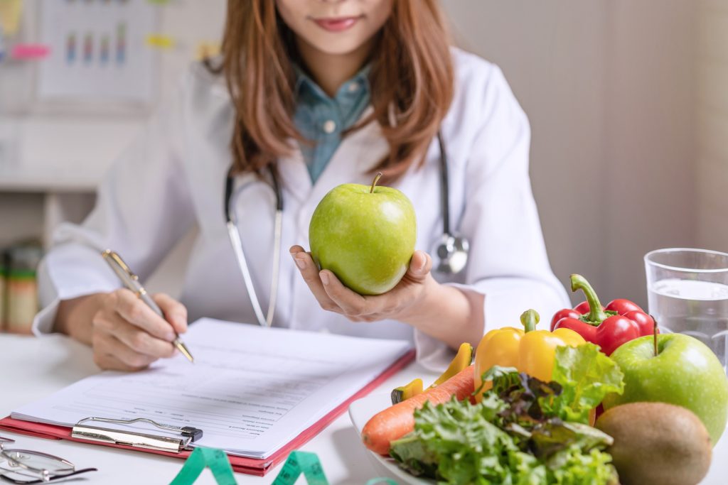 Dietitian holding apple while writing report